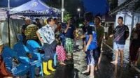 Kegiatan Komunitas di Malam Hari Sekelompok orang berkumpul di malam hari di jalan dengan kursi plastik biru.