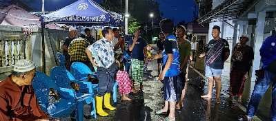 Sekelompok orang berkumpul di malam hari di jalan dengan kursi plastik biru.